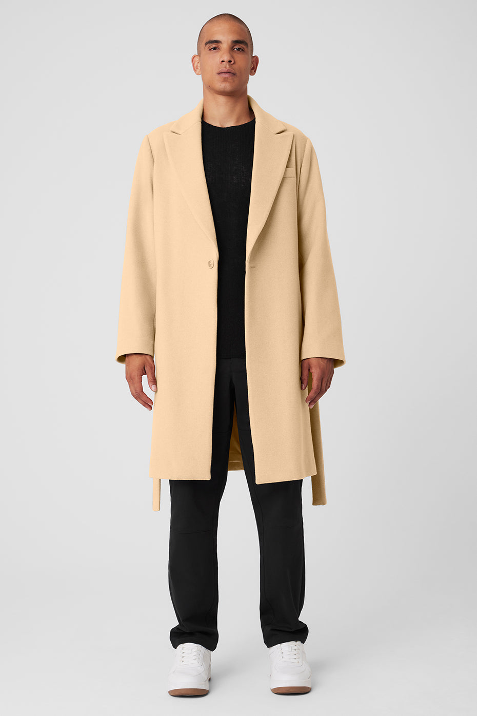 Side view of a camel wool coat with belt, styled over a suit for city wear