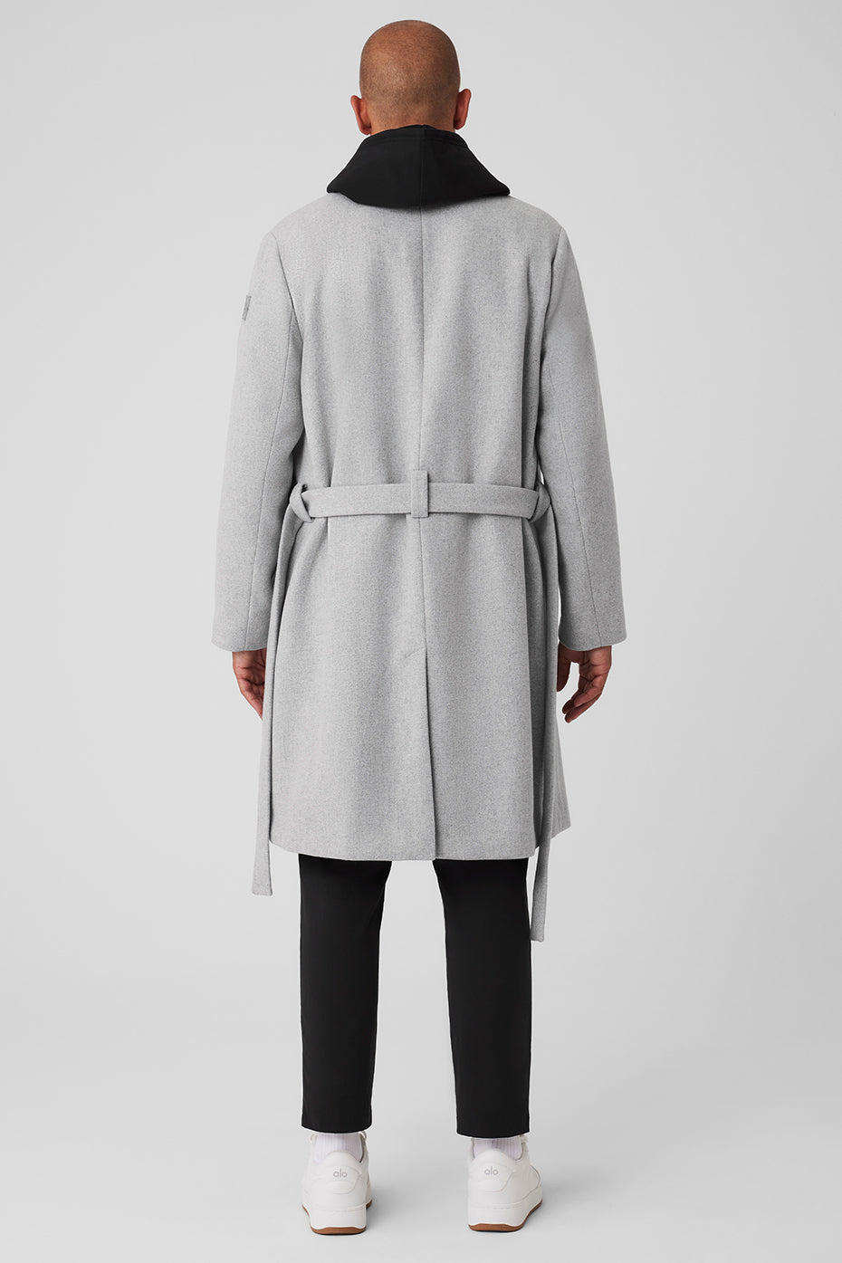 Side view showcasing the waist belt and straight fit of the wool coat.