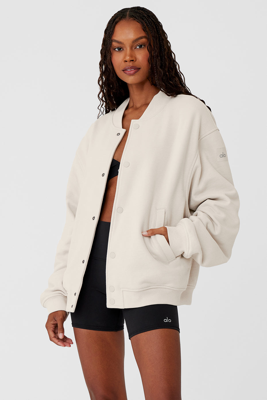 Front view of bone Letterman jacket hanging on a minimalist rack