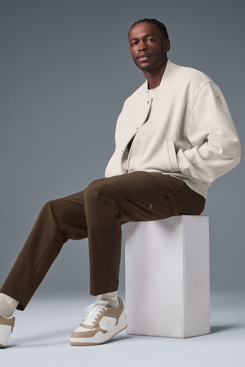 Front view of the mens varsity jacket in bone with drop shoulders and button closure