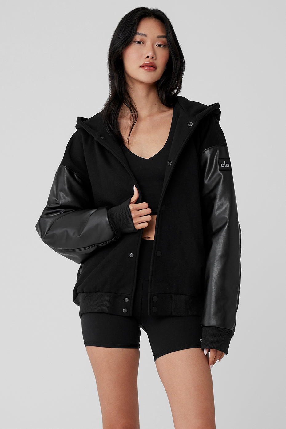 Black bomber jacket with hood styled for streetwear.