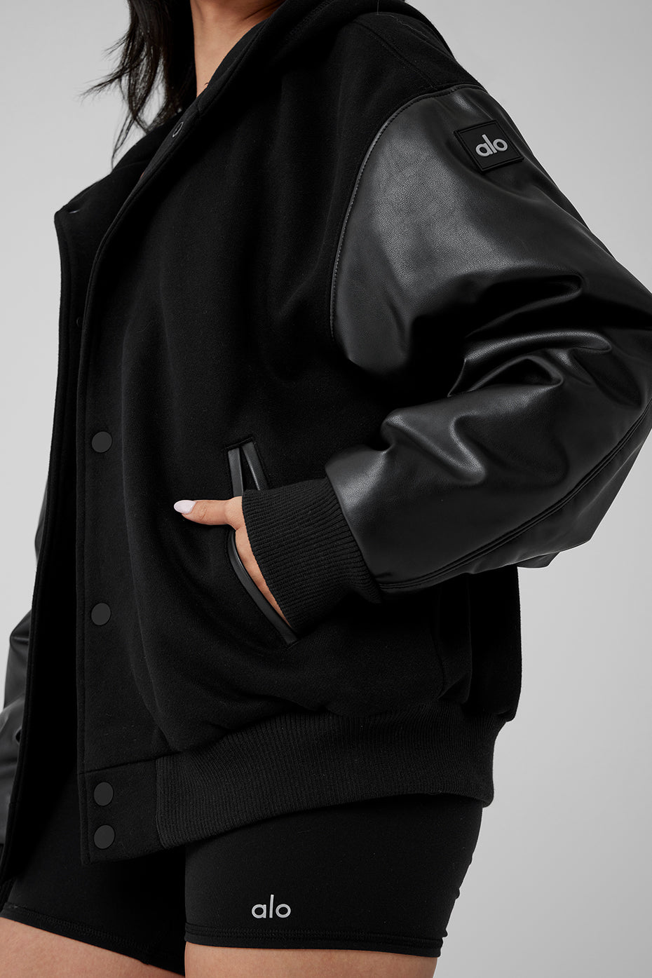 Black bomber jacket with hood styled for streetwear.