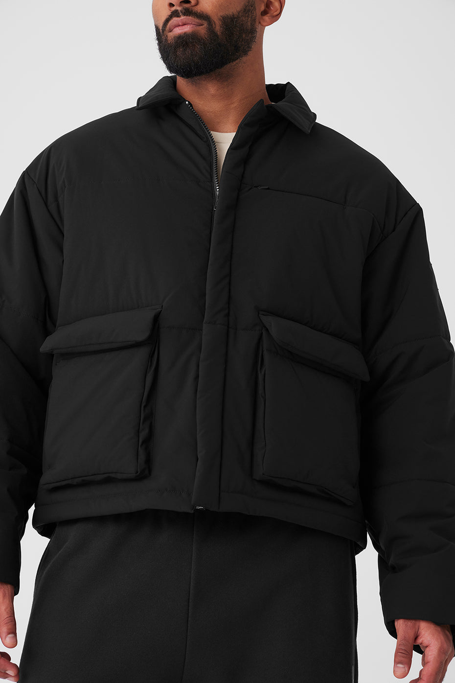 Black utility cargo jacket with oversized front pockets and sharp collar, styled for men and women