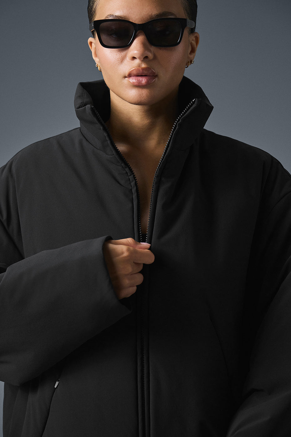 KUHL Stretch Voyagr Jacket in black, layered over a gray hoodie for urban cold weather.
