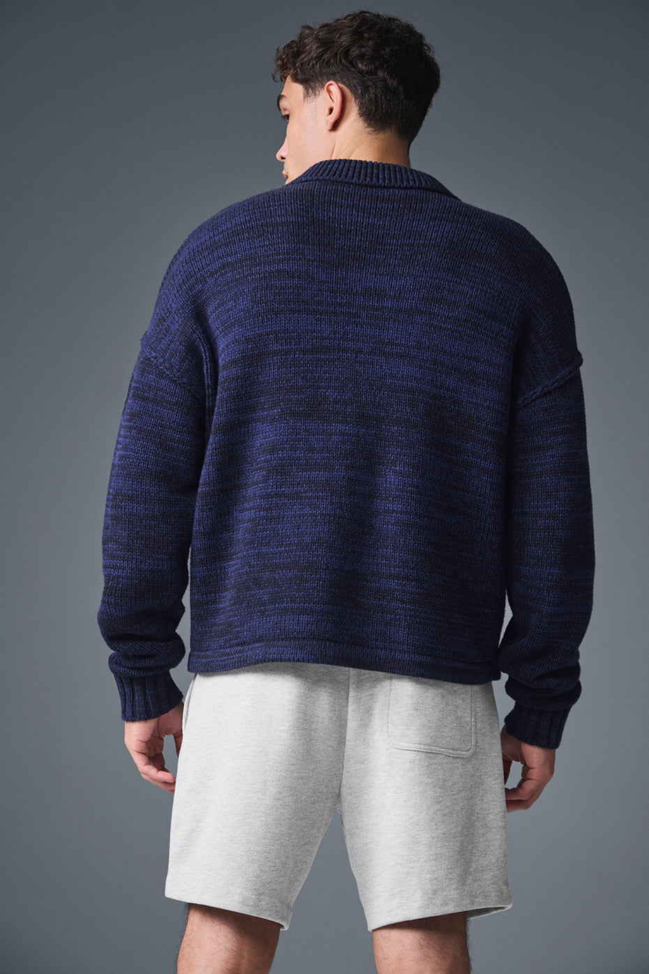 Side view highlighting the pockets and fit of the full zip sweater in a street style setting