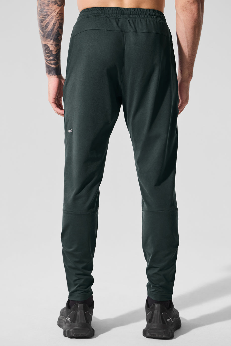 Close-up of Conquer fabric material on performance pants during stretch movement