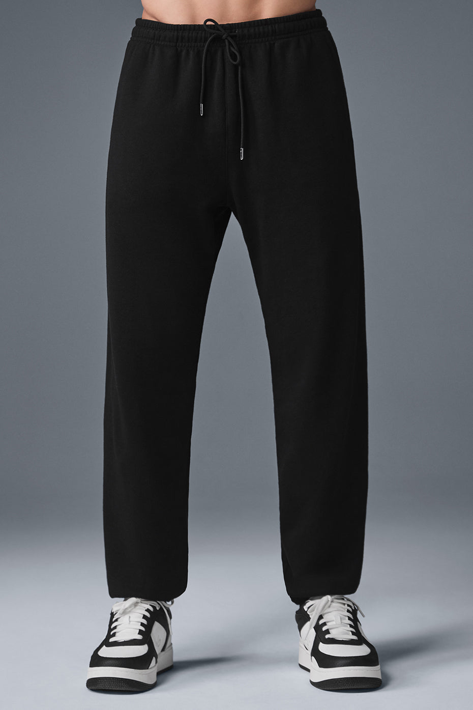 Front view of black sweatpants showcasing the cuffed design and drawcords.