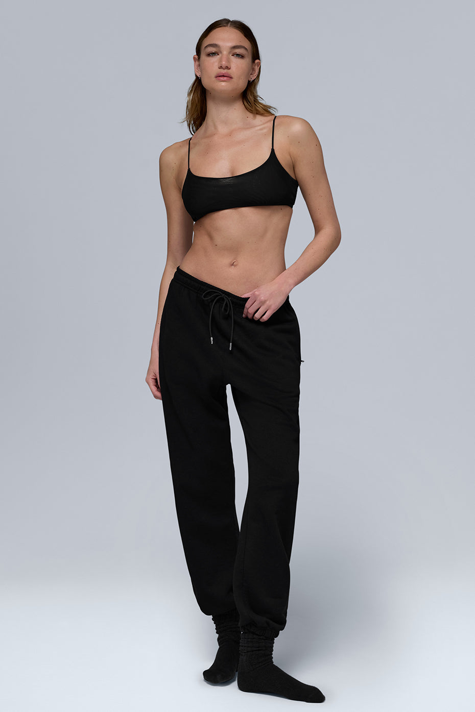 Black sweatpants folded on a wooden bench, showcasing cuffed hem