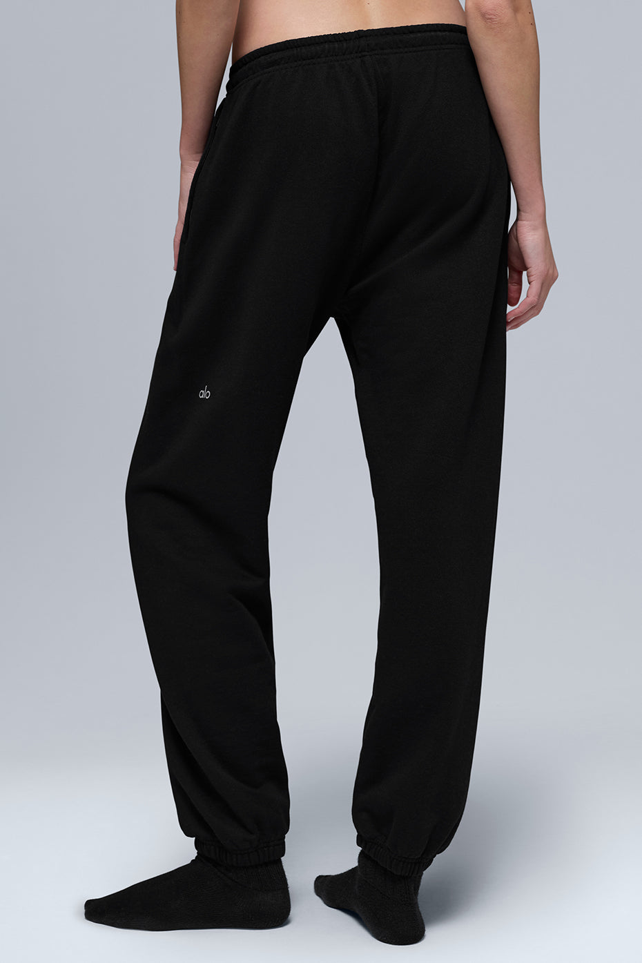Model wearing camo sweatpants mid-stride on a city sidewalk