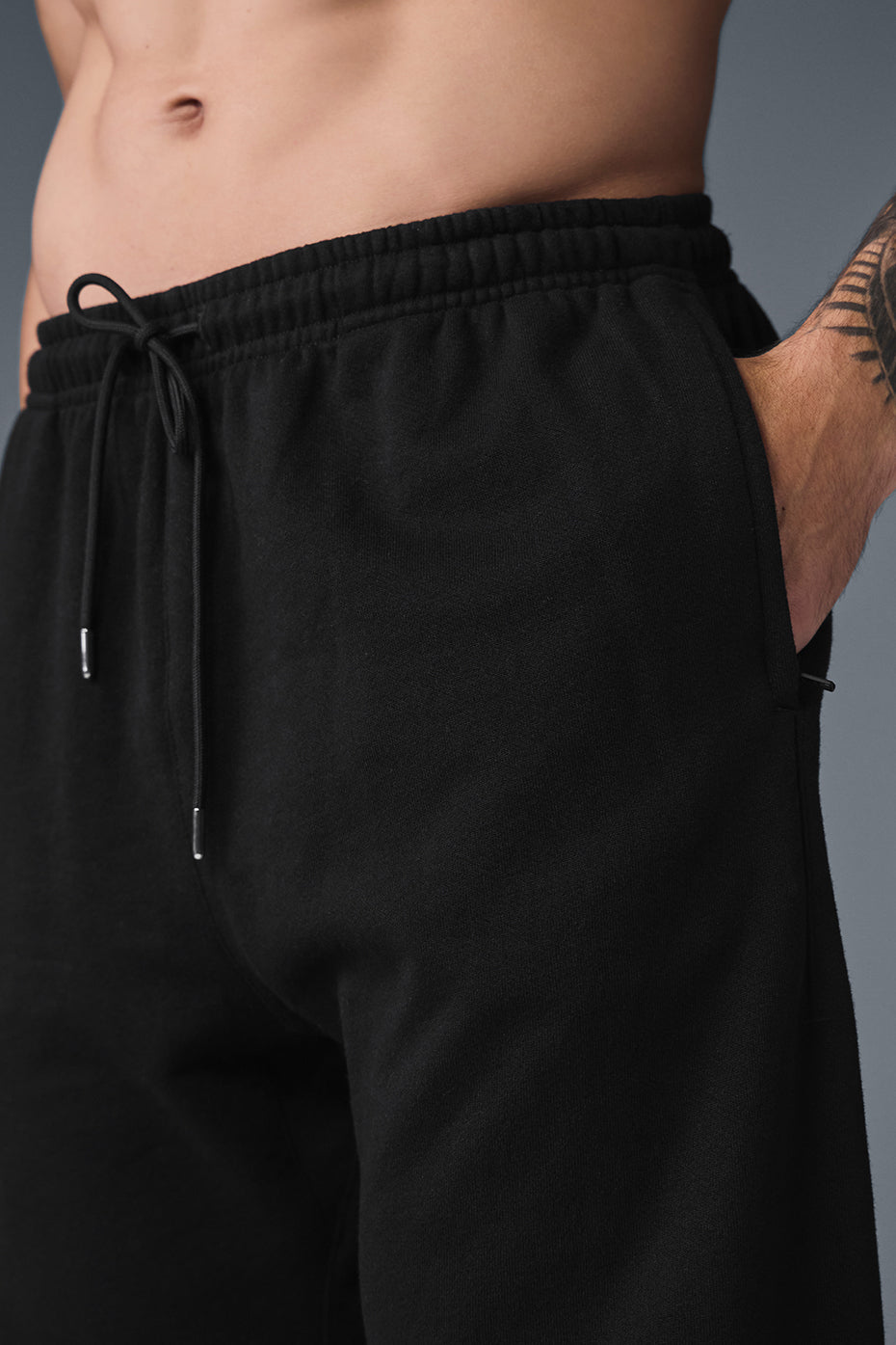 Front view of black sweatpants showcasing the cuffed design and drawcords.