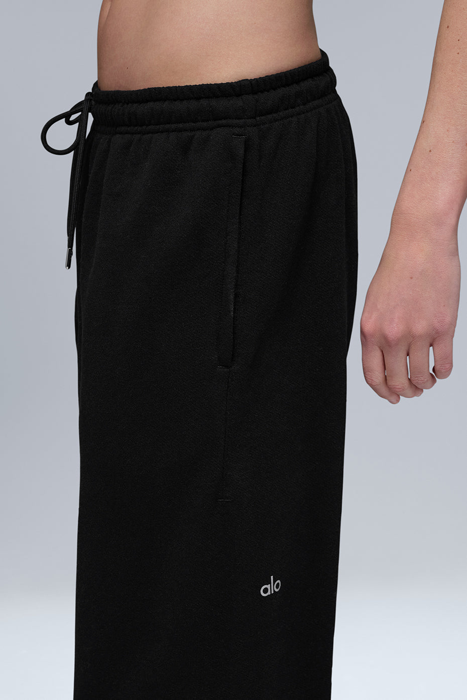 Black sweatpants folded on a wooden bench, showcasing cuffed hem