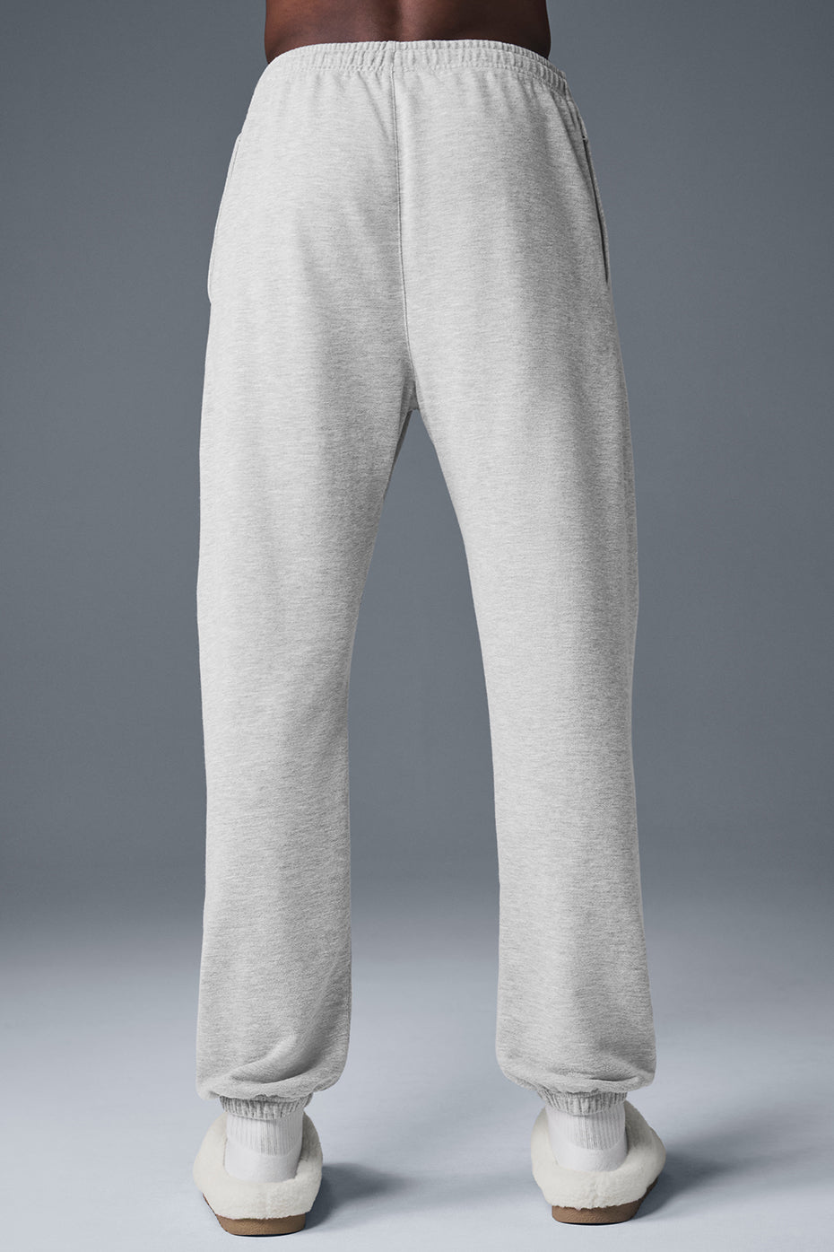 Front and back view of black sweatpants styled with white sneakers