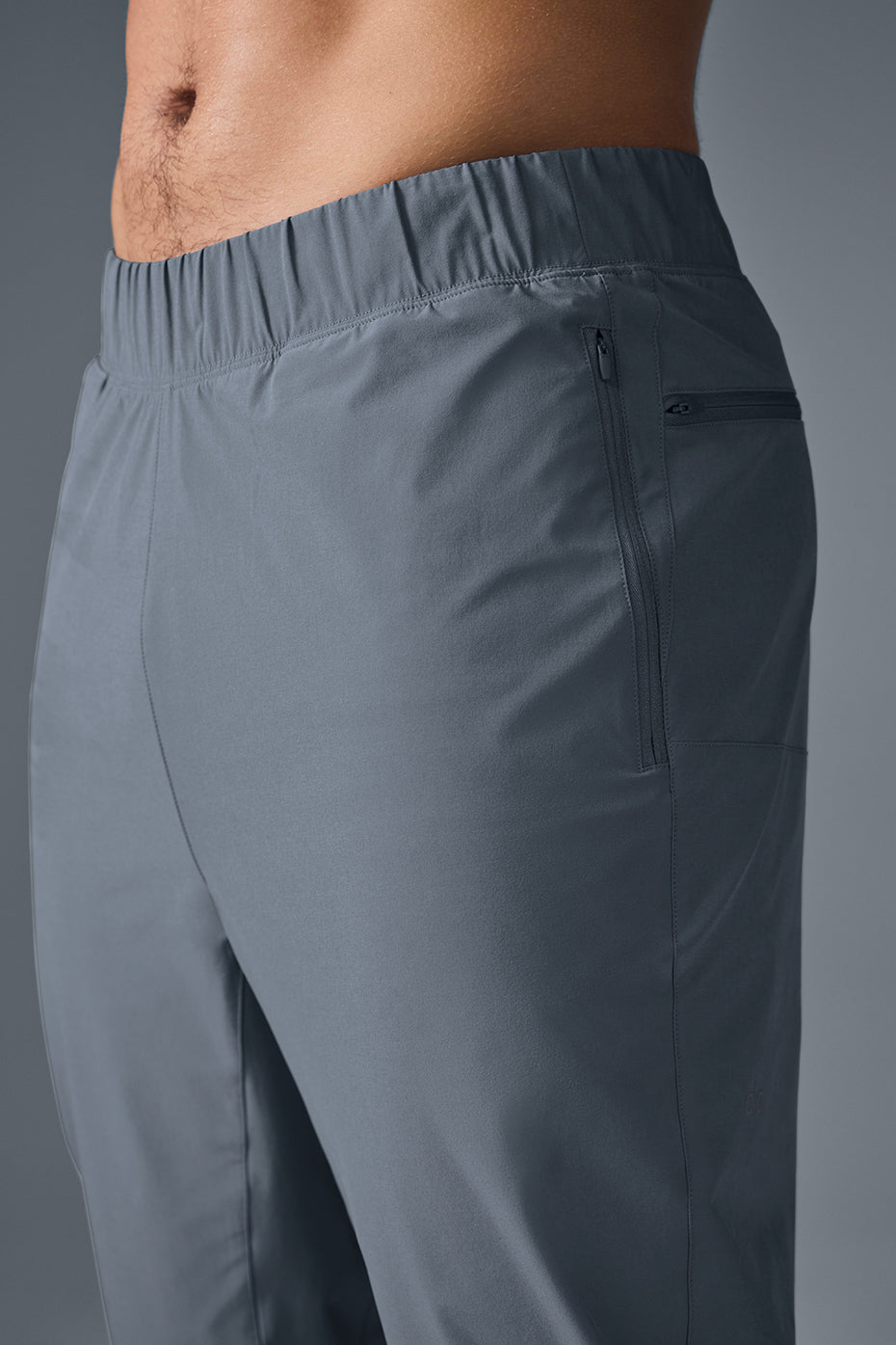Man modeling gray workout pants in an urban setting.