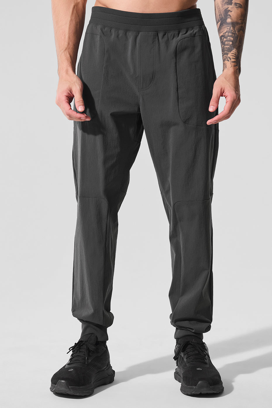 Side angle showing SummitFlex training trousers paired with trail shoes on a forest path.