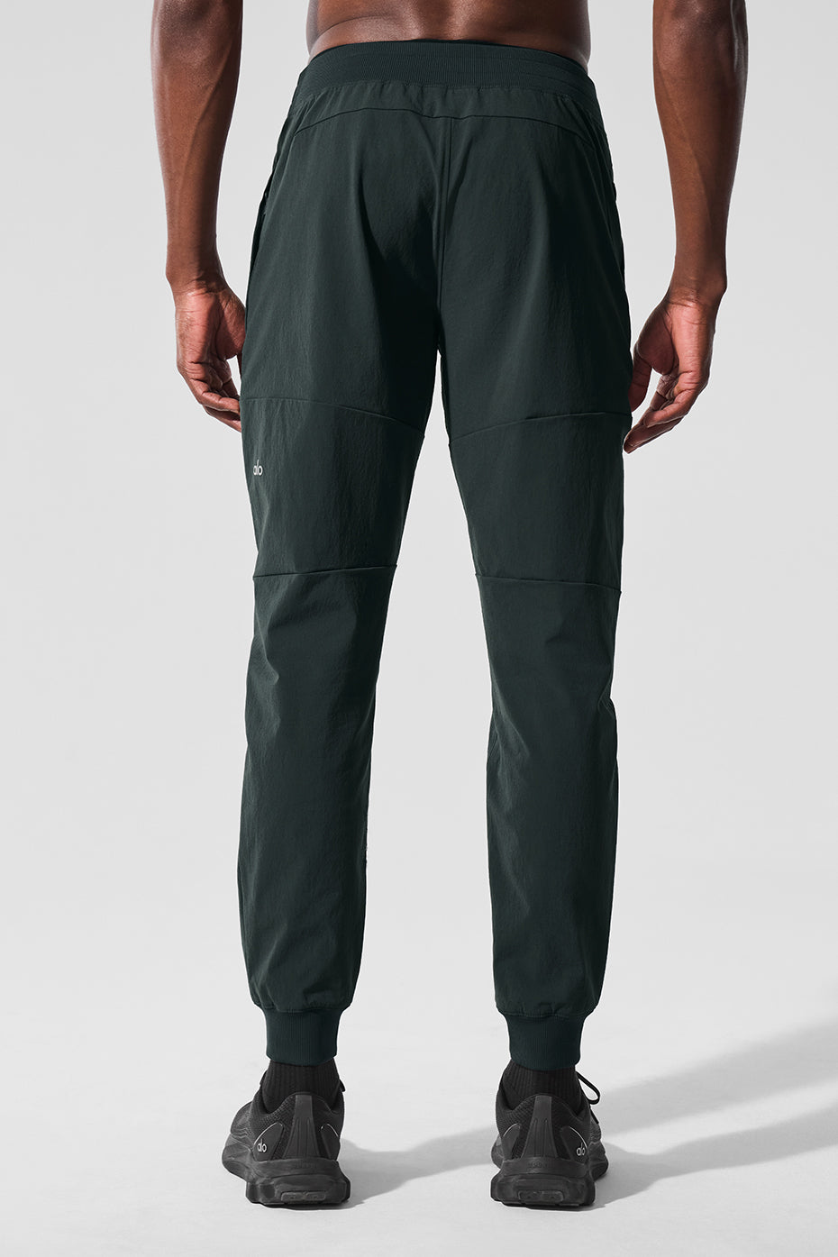Model demonstrating the elastic waistband and side zip pockets of performance mens pants