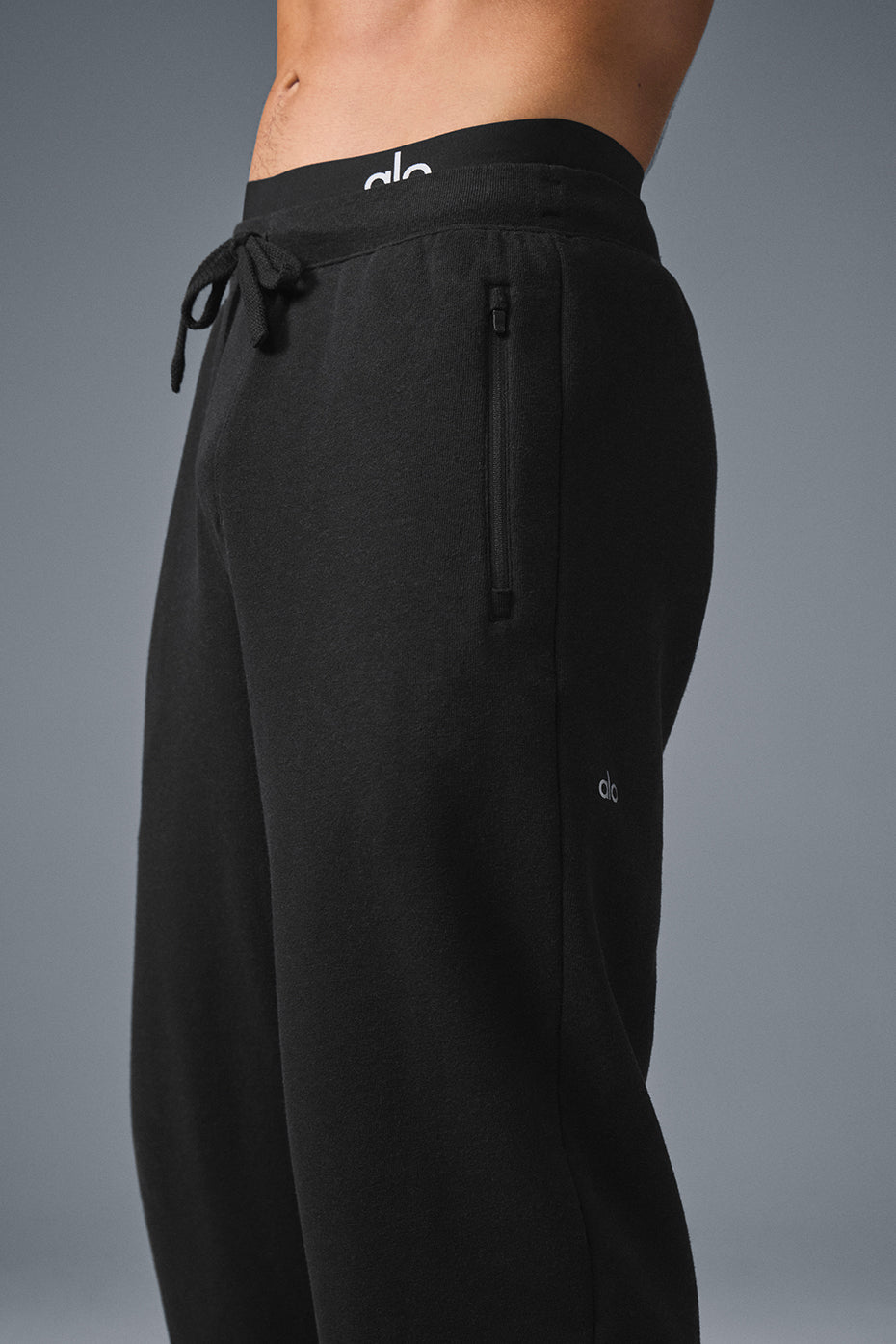 Lifestyle shot of grey sweatpants and camo sweatpants folded beside black pair