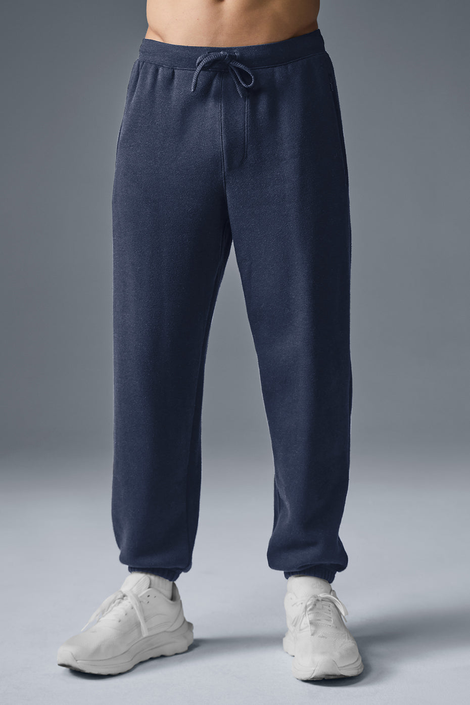 Front view of baggy navy sweatpants styled with athletic sneakers.