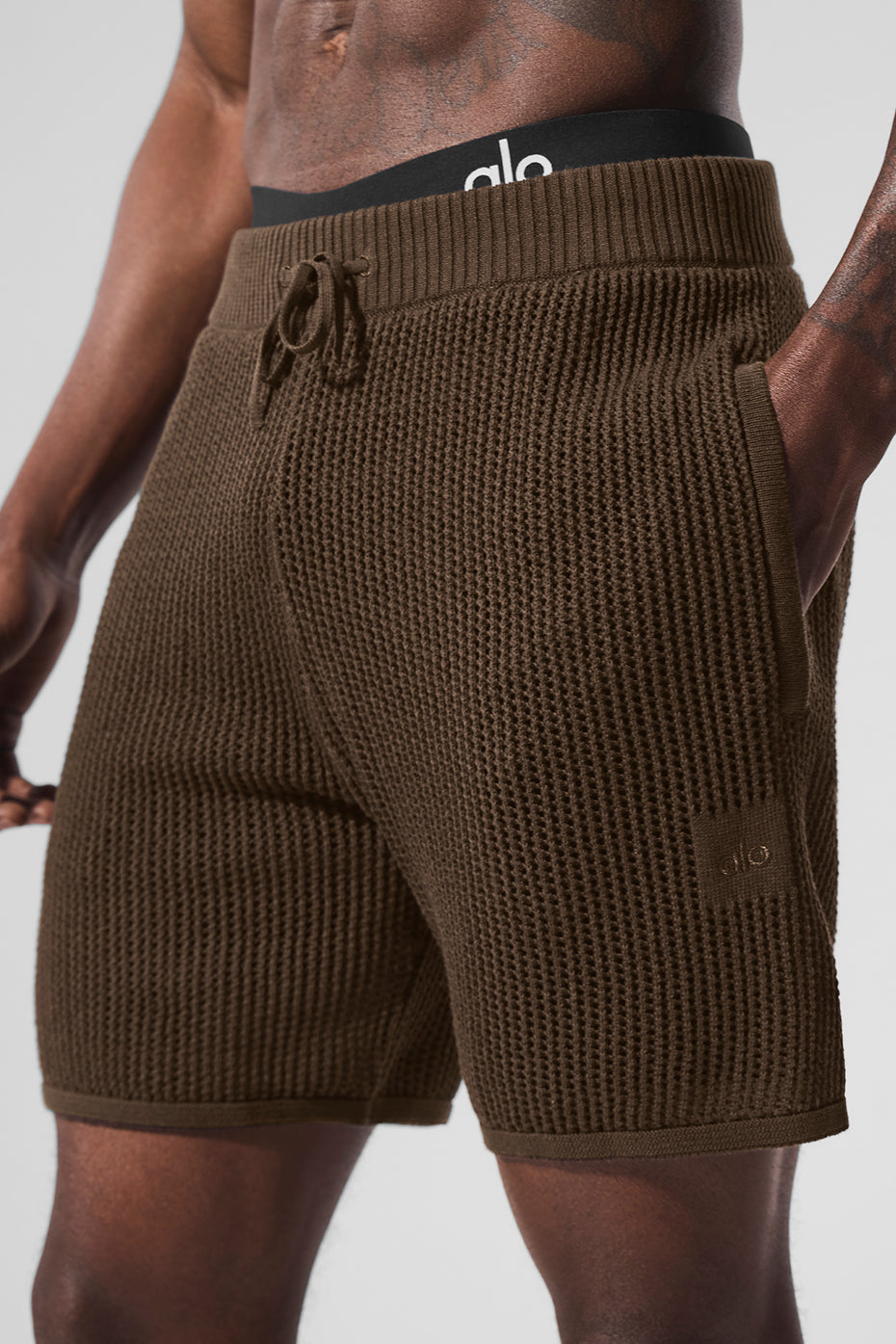 Model wearing summer shorts on a pier, highlighting zip pockets and movement-friendly fit