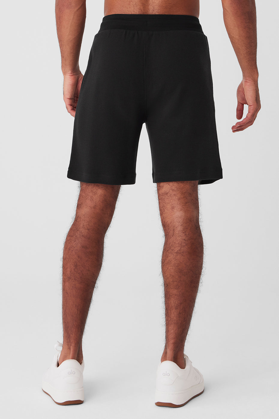 Man wearing black waffle shorts with a casual hoodie, sitting on a coffee shop patio
