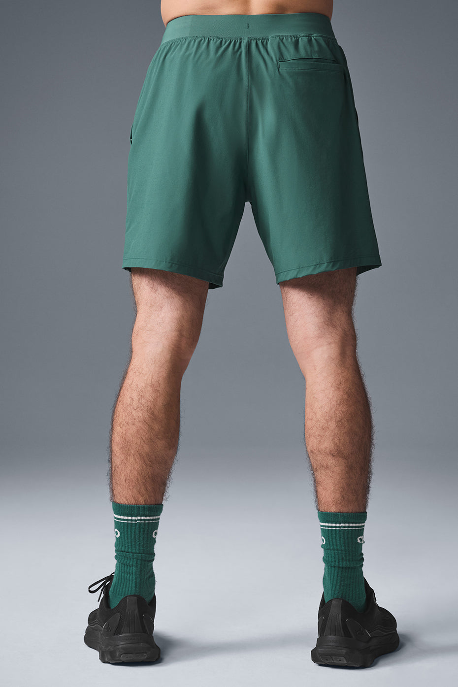 Back view of athletic shorts on male model walking Missouri trail with gear backpack