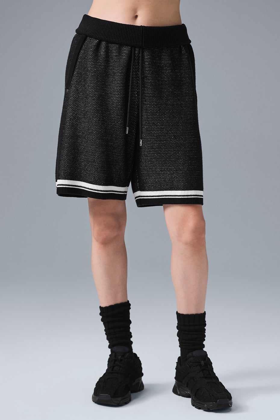 Model wearing black sweater knit shorts, styled with a matching sweater.