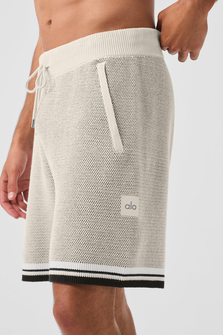 Side view highlighting the pockets of the sports club shorts in bone color.