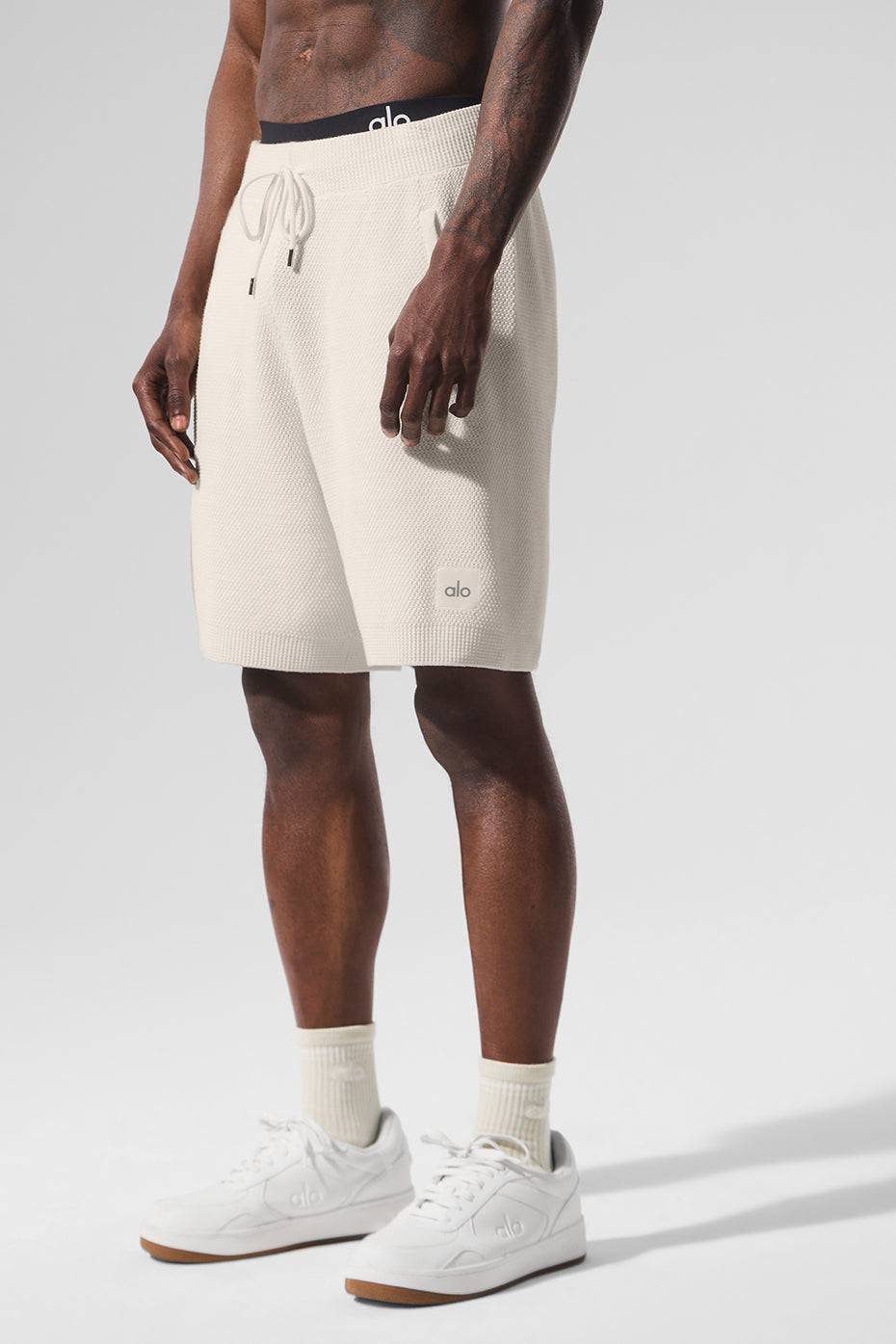 Model wearing ivory sweat shorts paired with a casual top