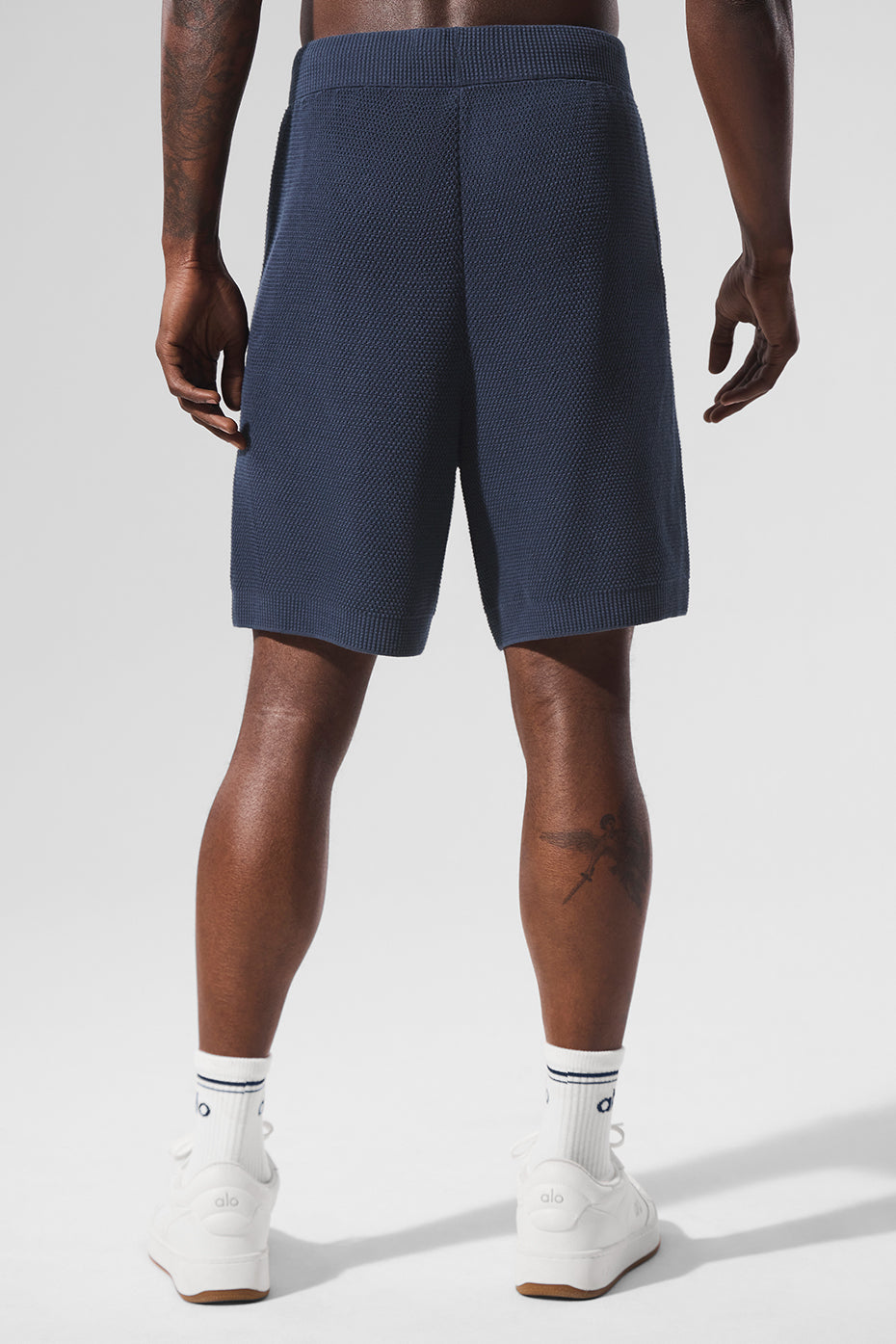 Model relaxing by the pool in navy sports club cotton knit shorts.