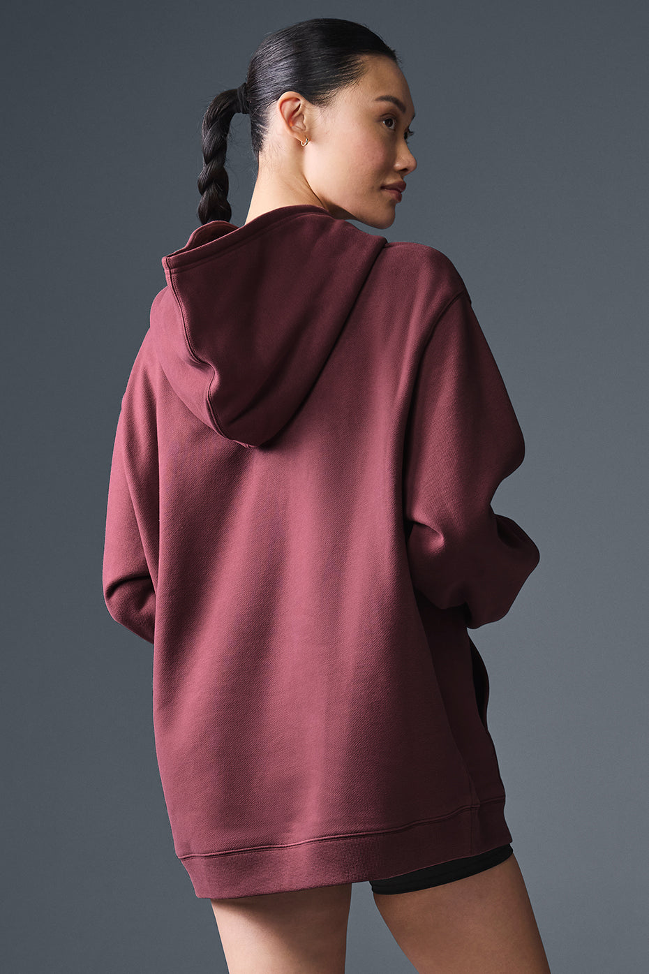 Model wearing oversized zip-up hoodie with urban backdrop.