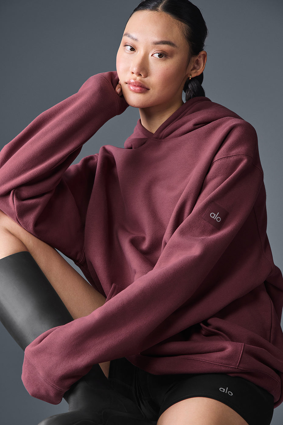 Model wearing oversized zip-up hoodie with urban backdrop.