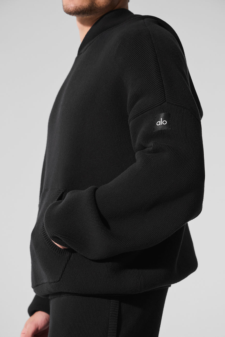 Front view of the black hooded sweater with knitted texture and kangaroo pocket