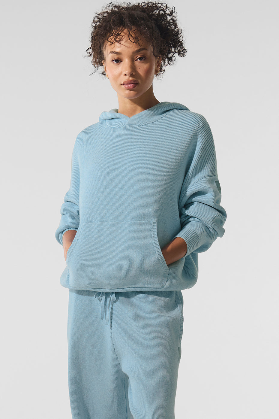 Front angle of blue spider hoodie styled with joggers on cozy porch setting