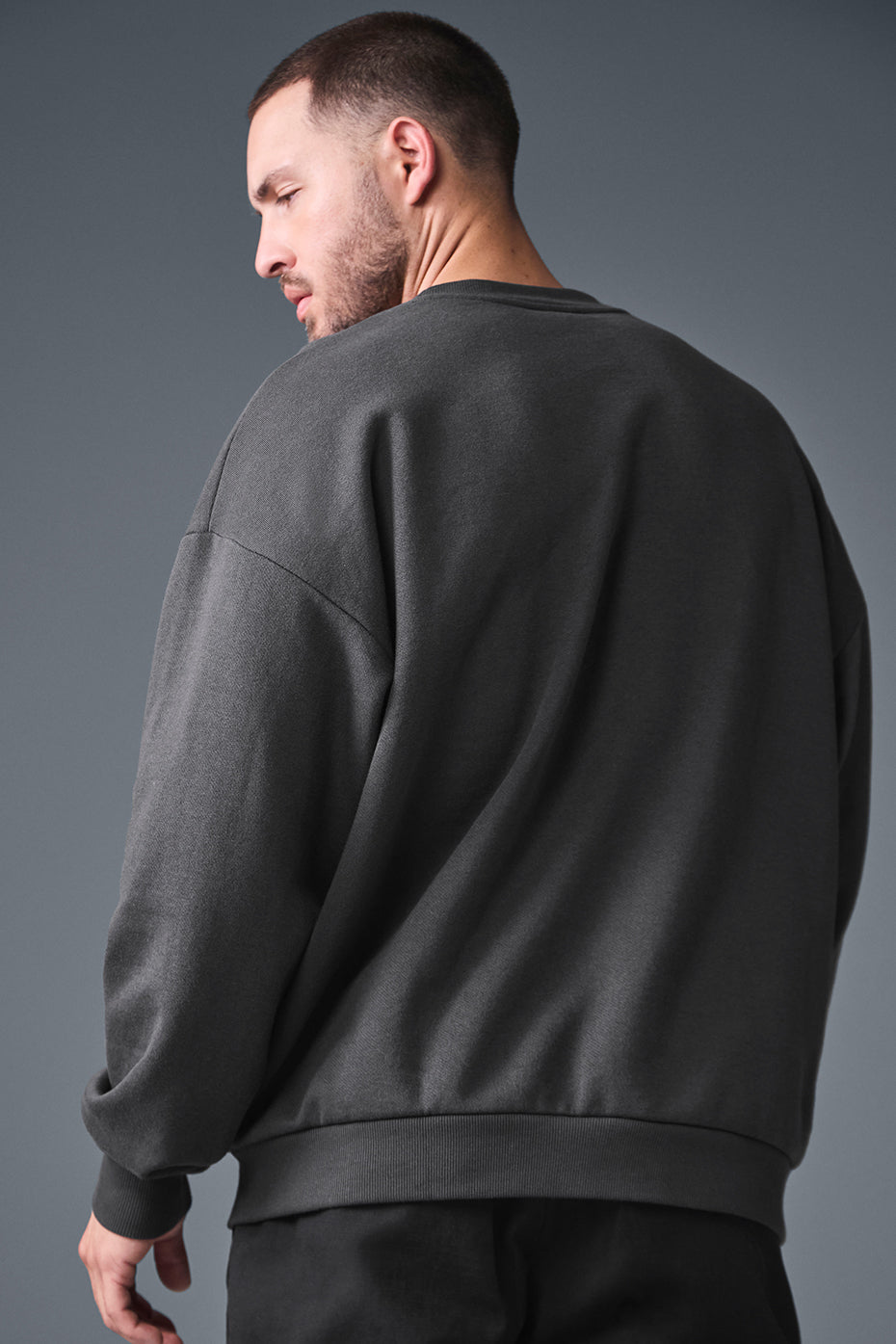 Close-up of the chrome ALO logo on the chest of the crewneck sweatshirt.
