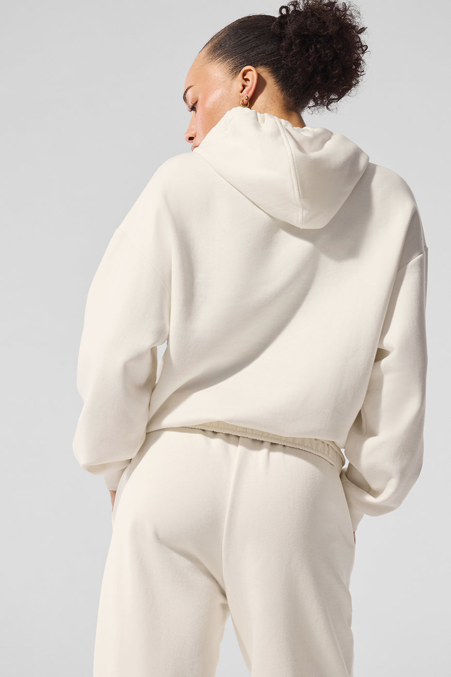 Model wearing ivory hoodie with relaxed fit, styled with neutral-toned joggers