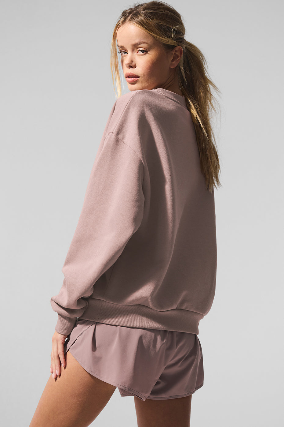 Side angle of the womens black sweatshirt, highlighting the ribbed cuffs and hem.
