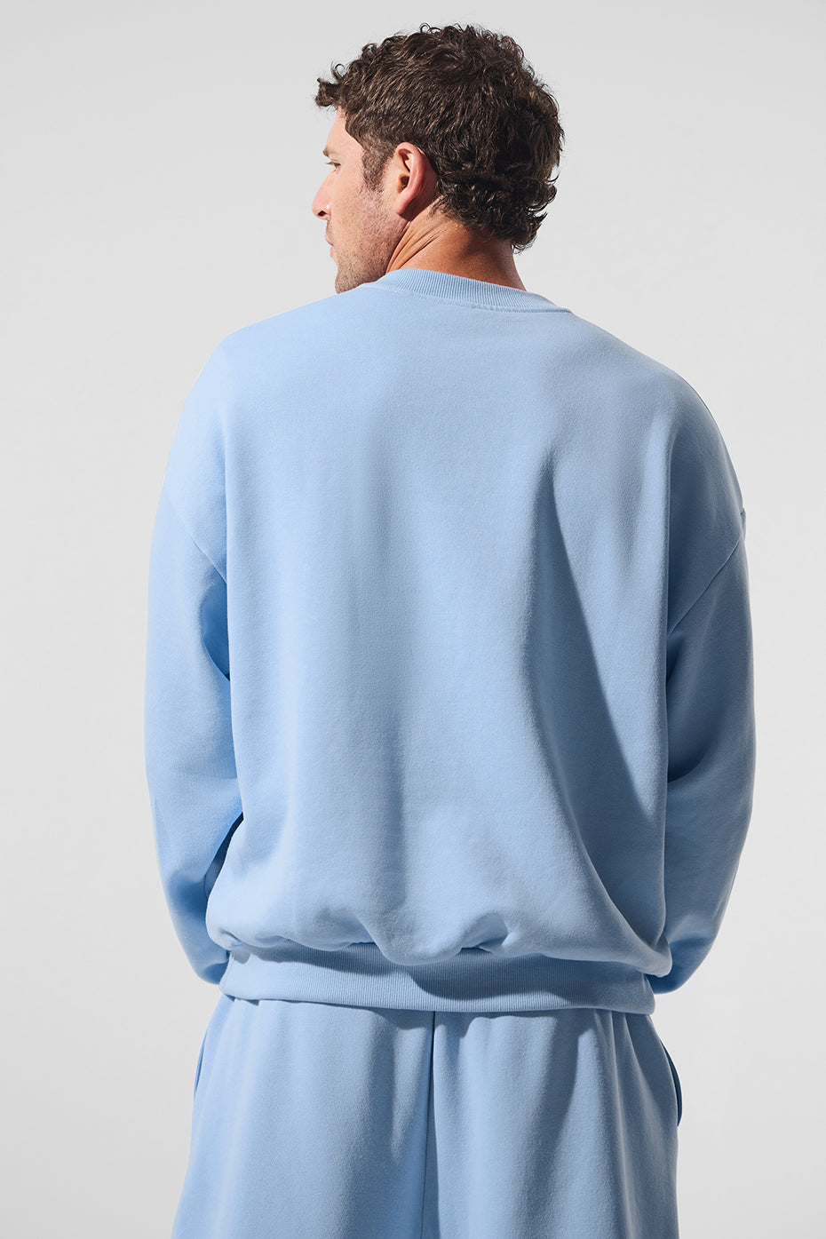 Close-up of the chrome ALO logo on the chest of the crew neck pullover
