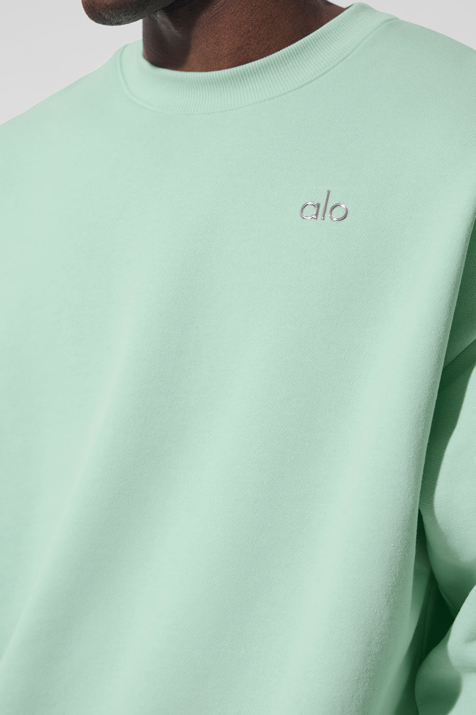 Close-up of the ALO logo on the chest of the crew neck pullover.