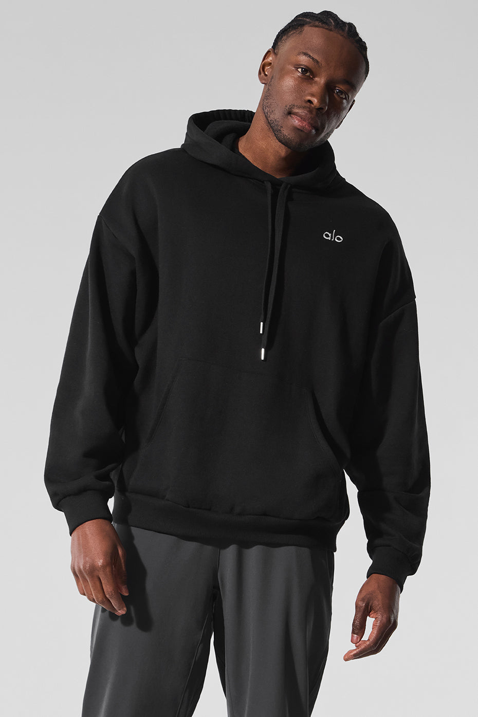 Close-up of the kangaroo pocket and ribbed cuffs of the black hoodie.