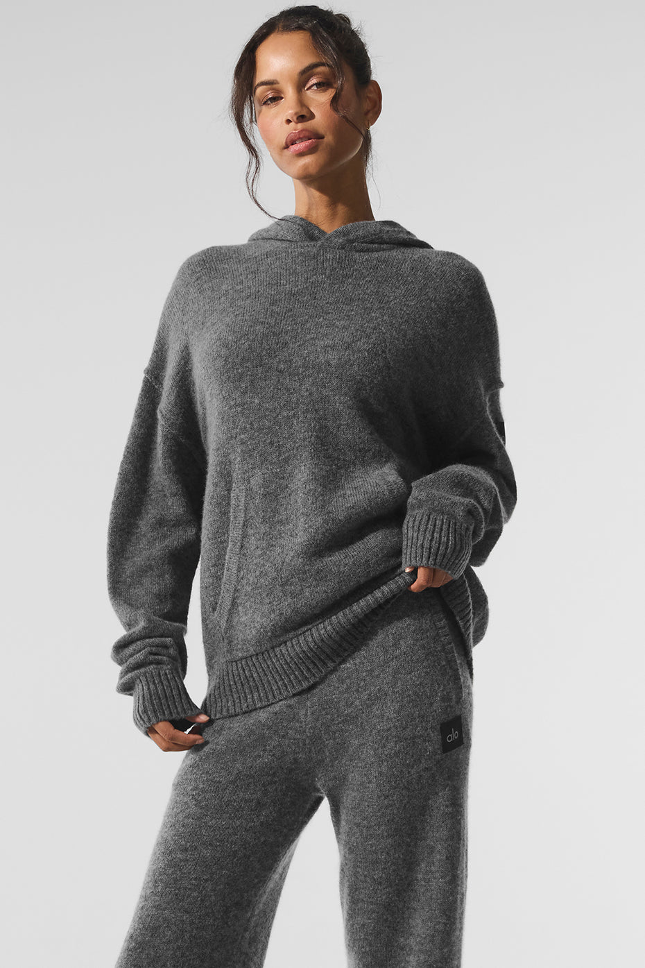 Model wearing a platinum grey cashmere hoodie in a cozy lounge setting