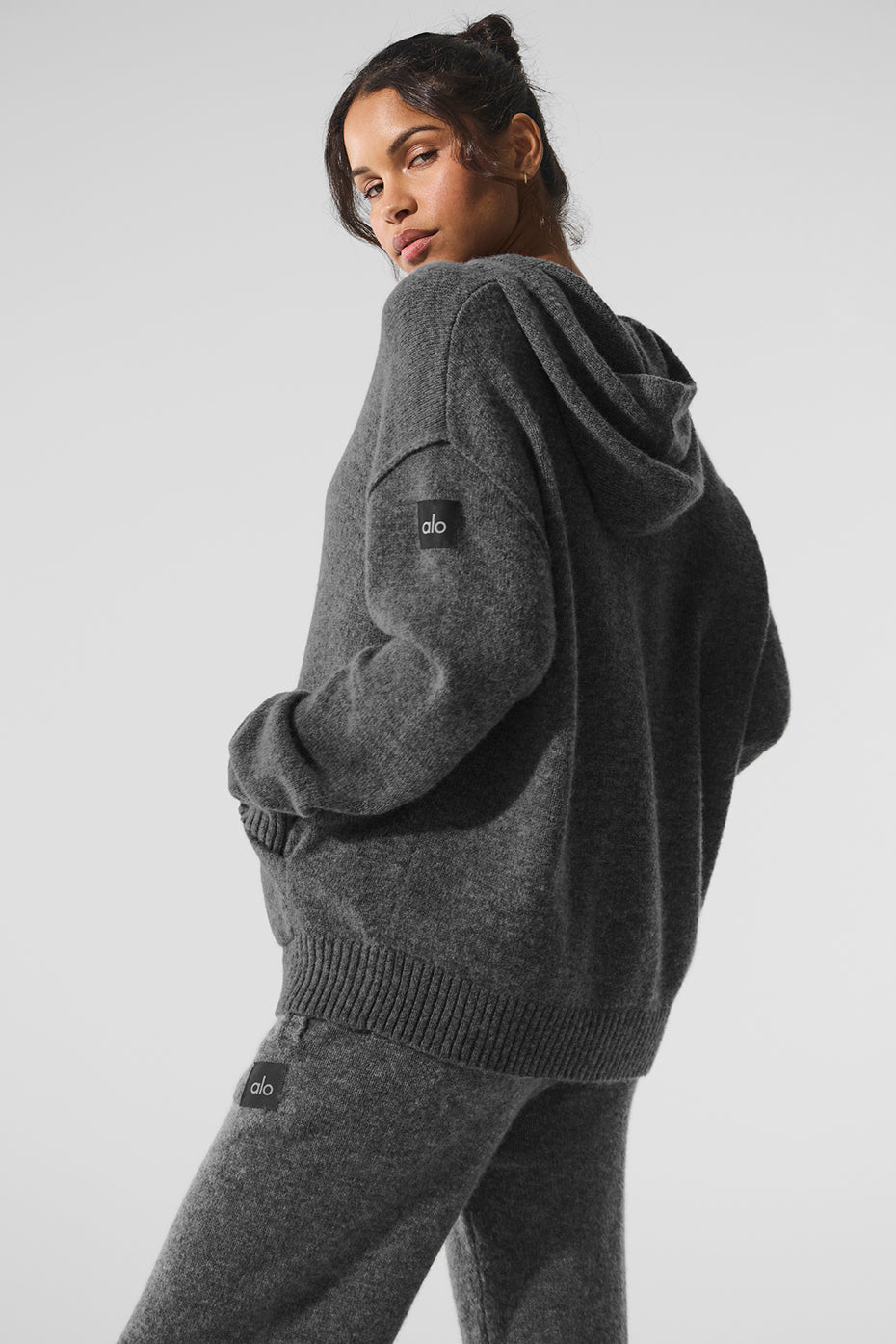 Model wearing a platinum grey cashmere hoodie in a cozy lounge setting