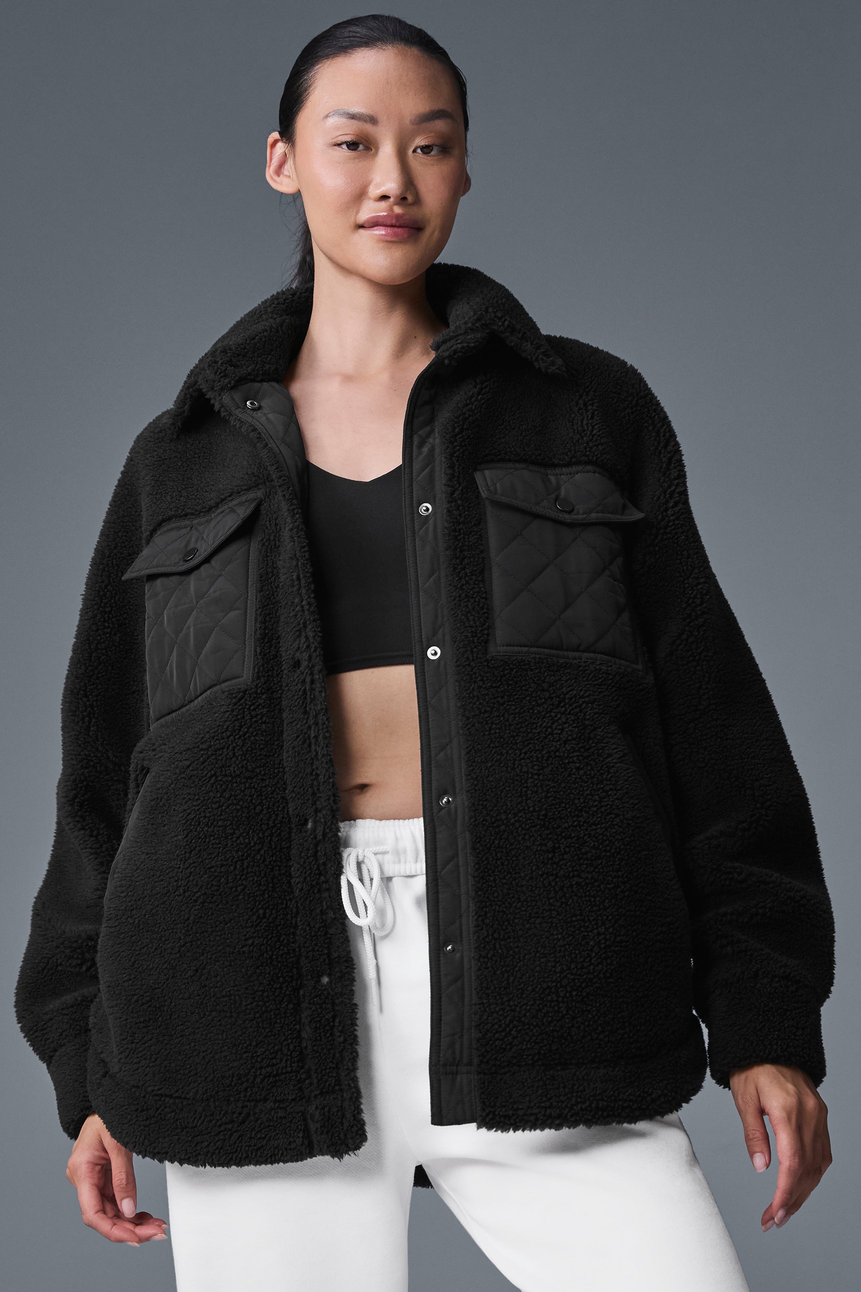 Close-up of black shacket showing quilted flap pockets and elbow patches