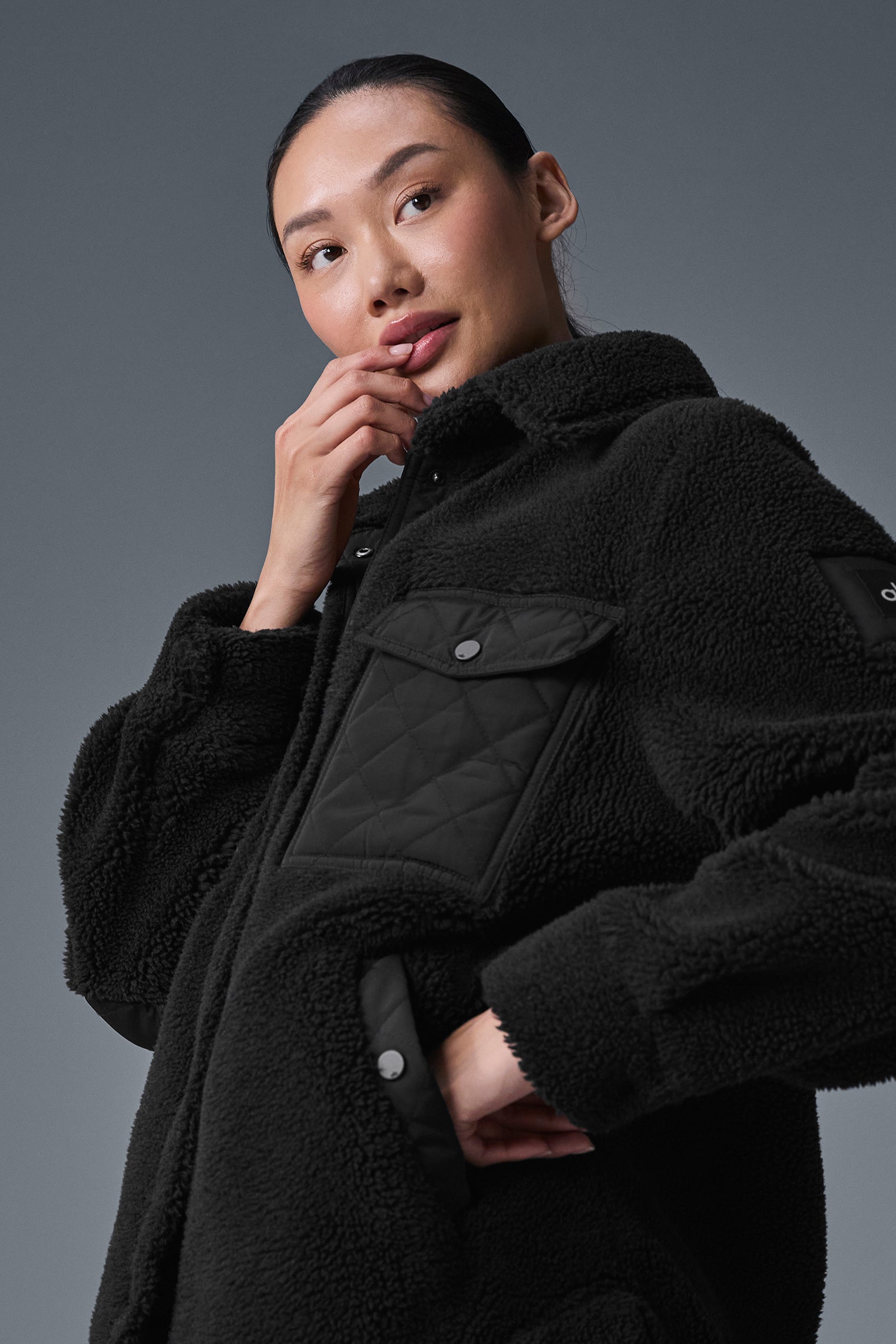 Close-up of black shacket showing quilted flap pockets and elbow patches