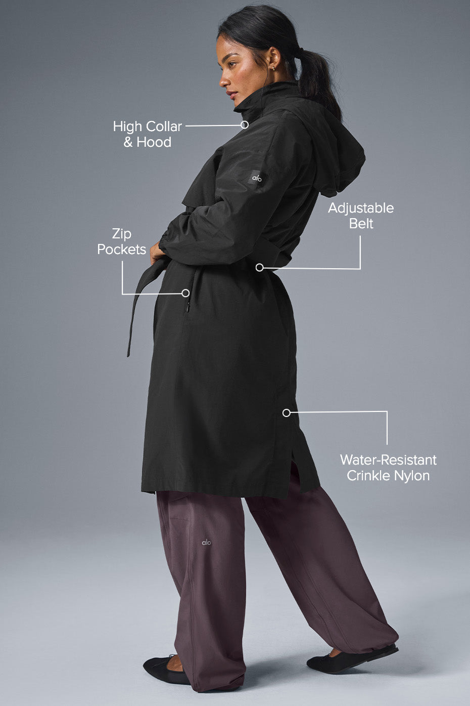 Model walking in the rain wearing a black trench coat and rain boots