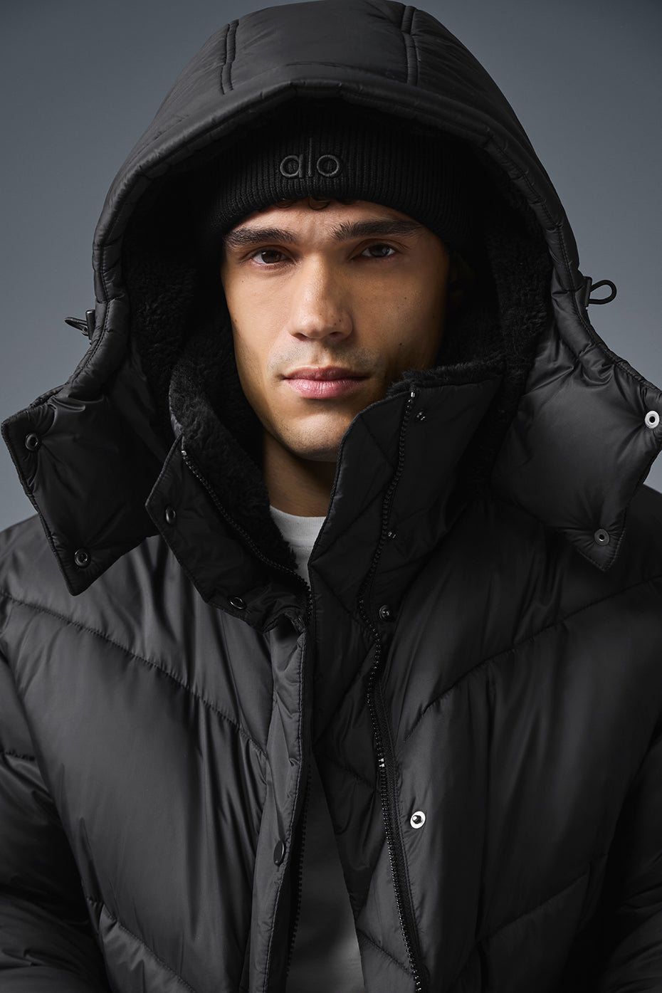 Model wearing the black puffer jacket with hood in a winter setting.