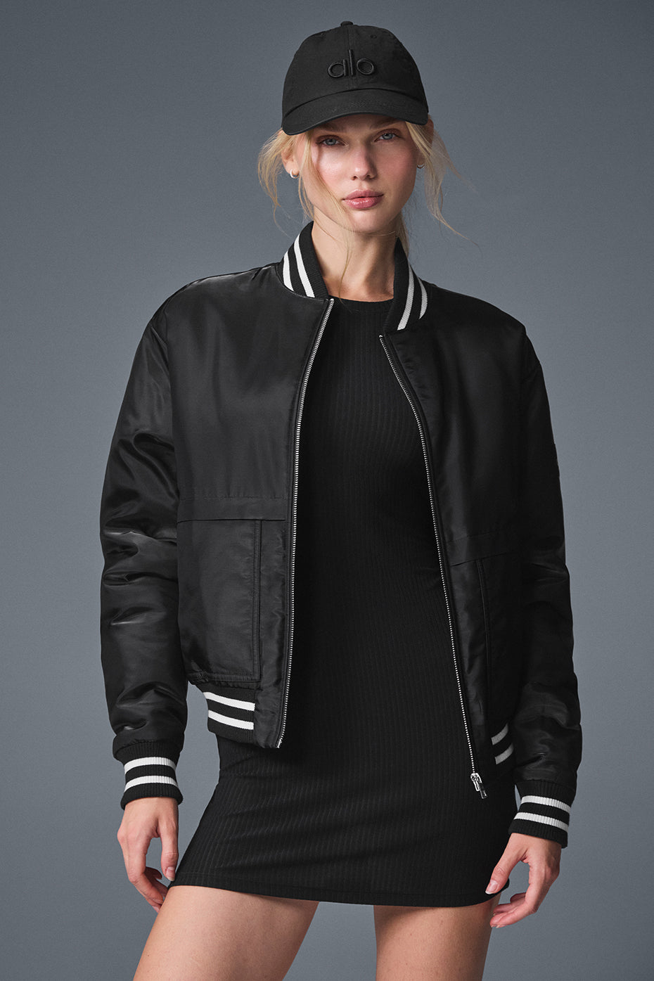 Women’s black bomber jacket styled with jeans and sneakers for a casual look.