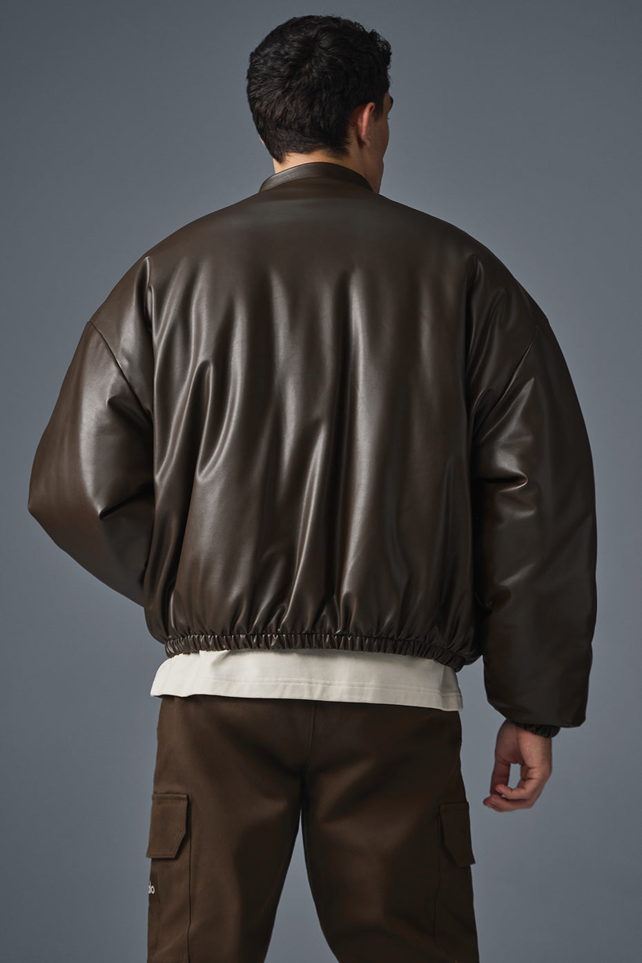 Model wearing faux bomber leather jacket over cozy sweater during autumn walk