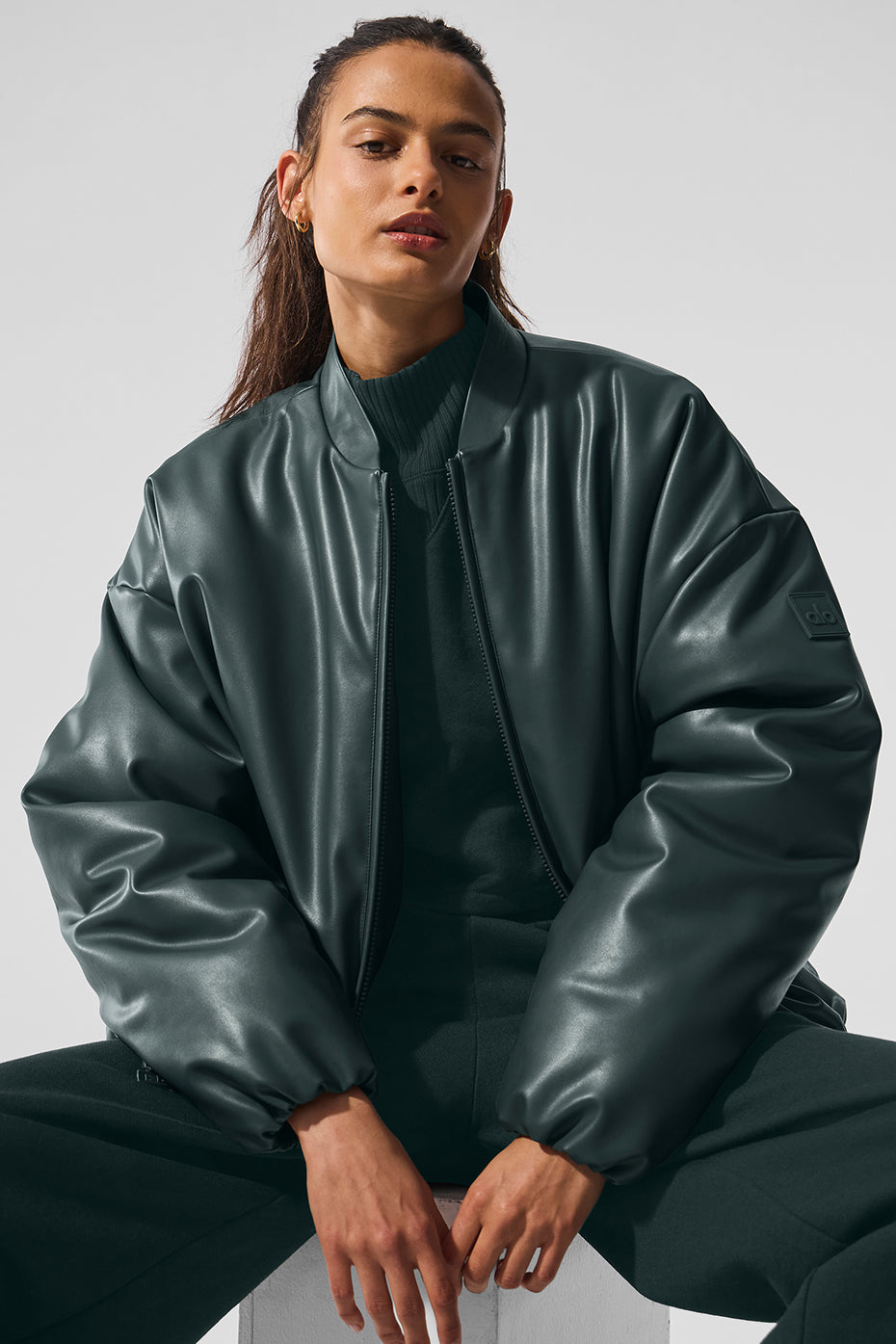 Close-up of the premium faux leather texture on the charcoal green bomber jacket
