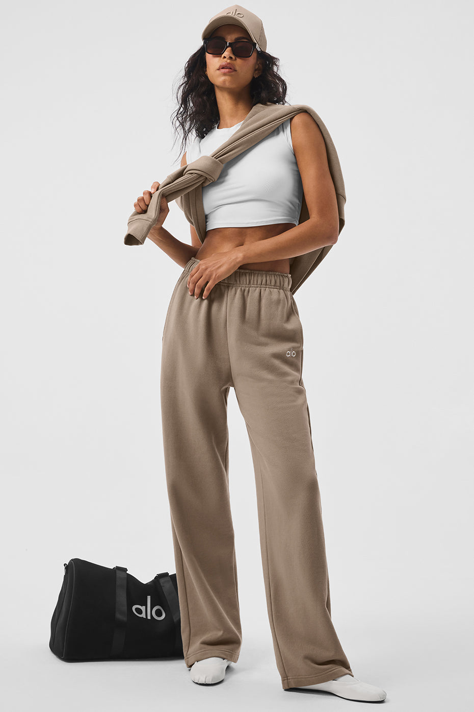 Men wearing black straight leg sweatpants with white sneakers in urban setting