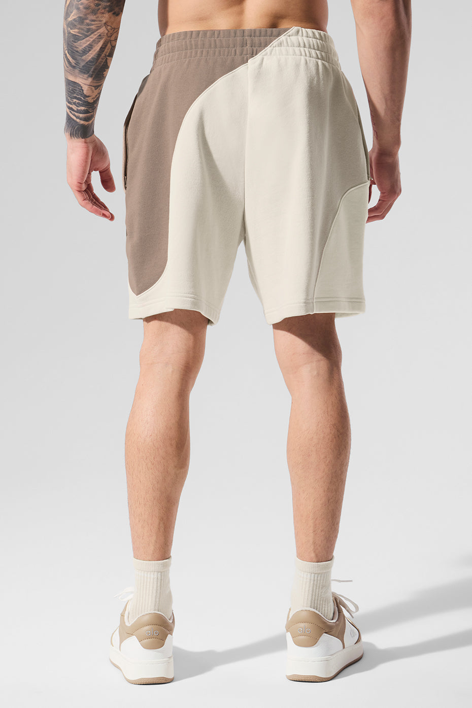 Flat lay of ivory/bone/gravel shorts paired with gym shoes and tee, suggesting activewear versatility.