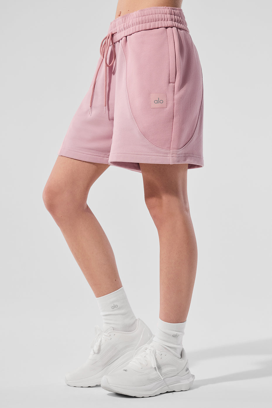 Model wearing sunset pink fleece shorts, ideal for summer outings.